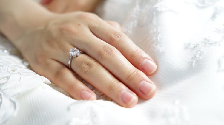 A woman's hand on a pillow displaying her engagement ring