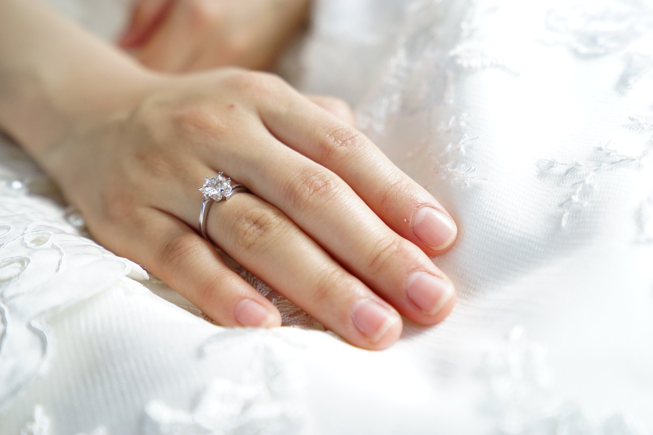A woman's hand on a pillow displaying her engagement ring