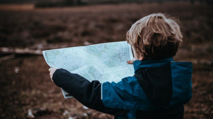 Child holding out a map and looking at it