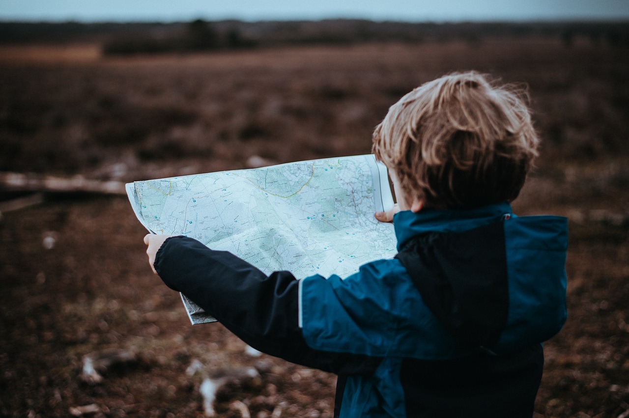 Child holding out a map and looking at it