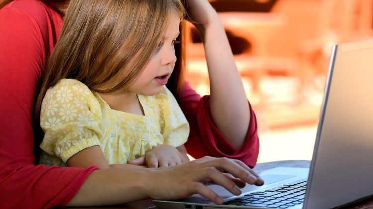 Child in their parent's lap using a laptop