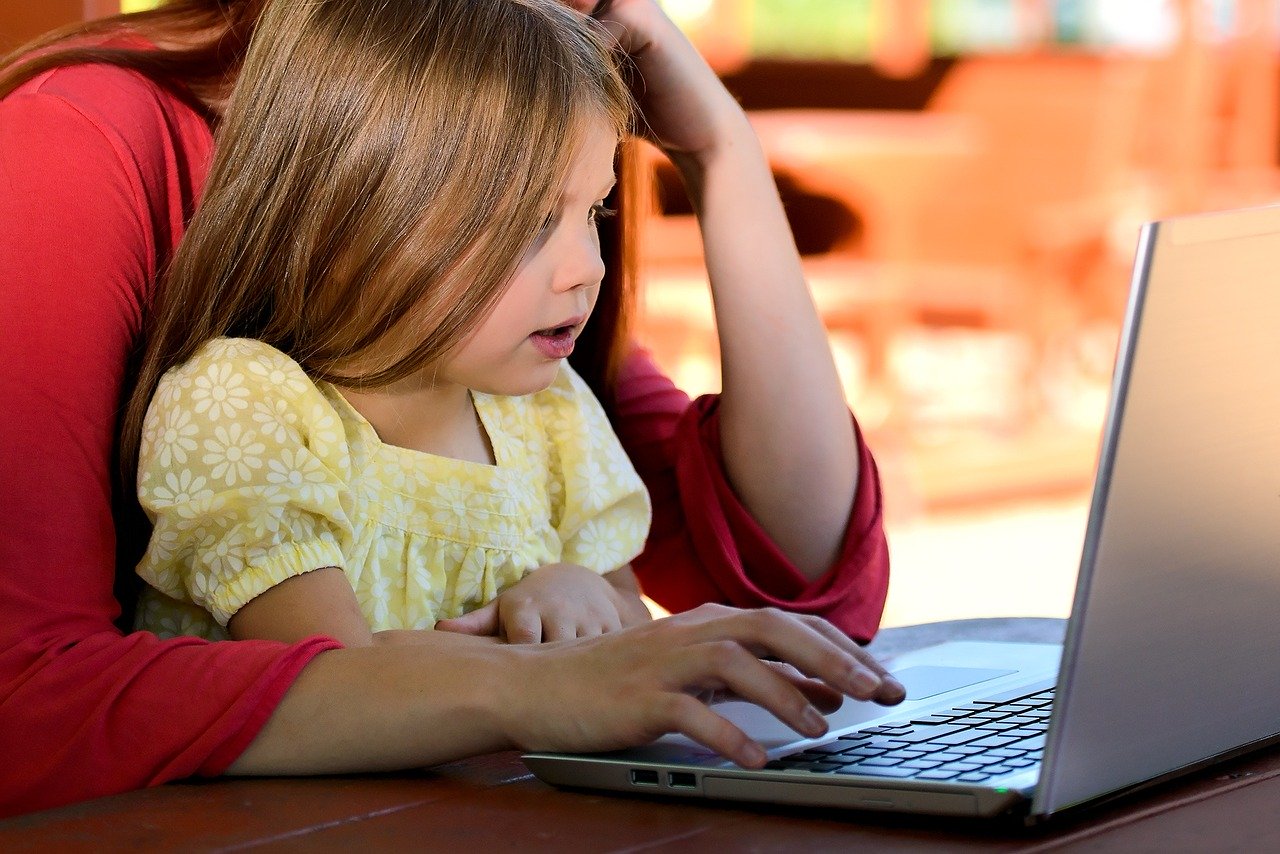 Child in their parent's lap using a laptop